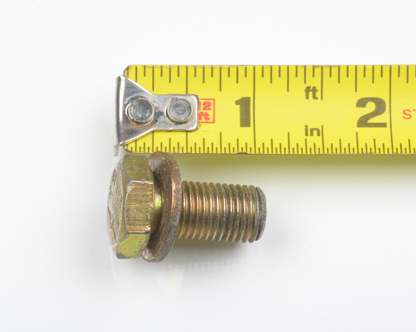 Metal bolt with hex head and washer, measured by a tape measure on a white background